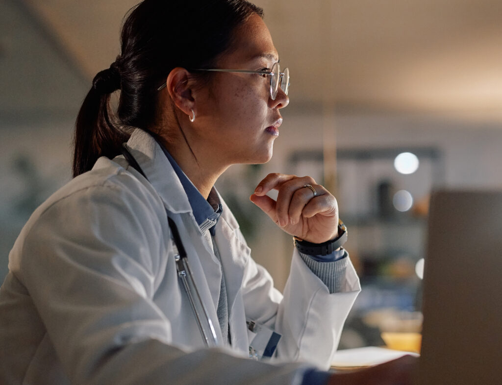 Computer, thinking and doctor asian woman in hospital at night for medical, research or learning. Healthcare, mri scan on screen with young medicine professional in office of clinic for neurology